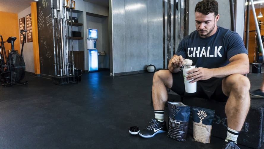 Man scooping protein powder into shaker bottle